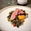 tender duck breast slices on a plate with morel mushrooms, peas, and sliced cherry tomatoes