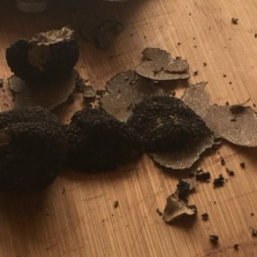 finely sliced black truffle on a wooden cutting board